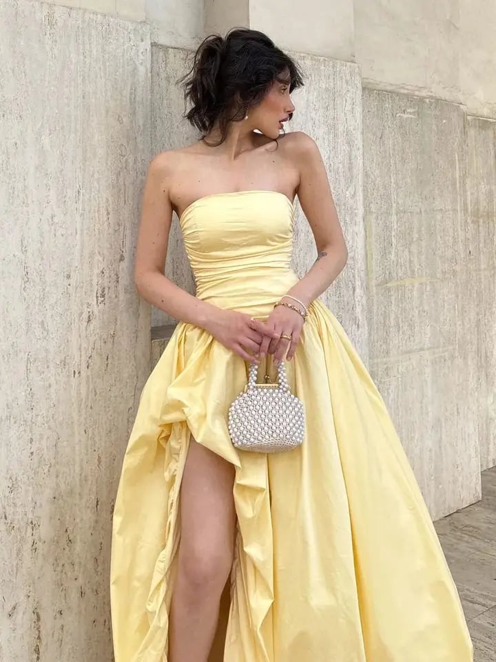 Elegantní žluté plisované šaty bez ramínek s vysokým pasem a rozparkem pro společenské akce